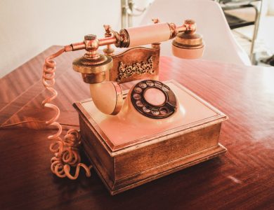 white and brown rotary telephone on brown wooden table