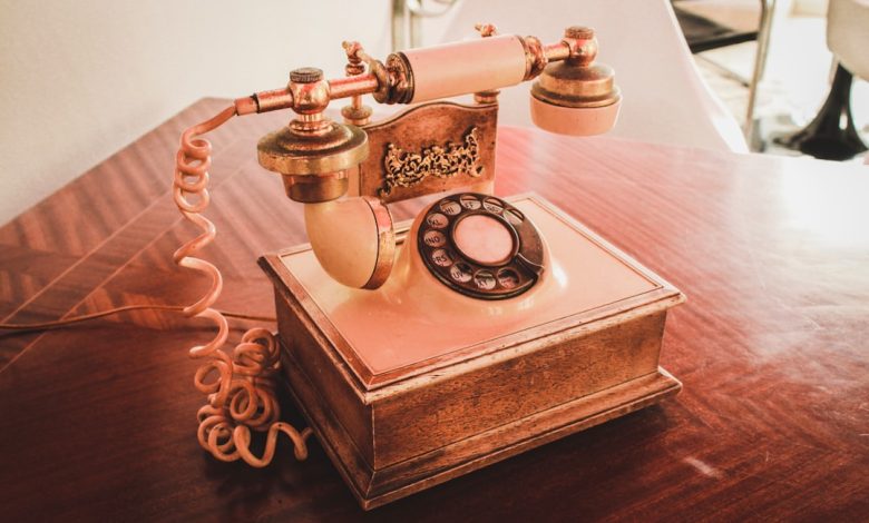 white and brown rotary telephone on brown wooden table