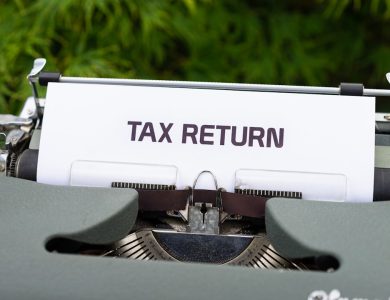 a close up of a typewriter with a tax return sign on it