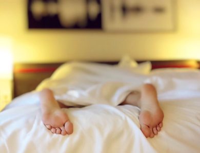 A person relaxing on a bed with feet under white sheets, conveying serenity.