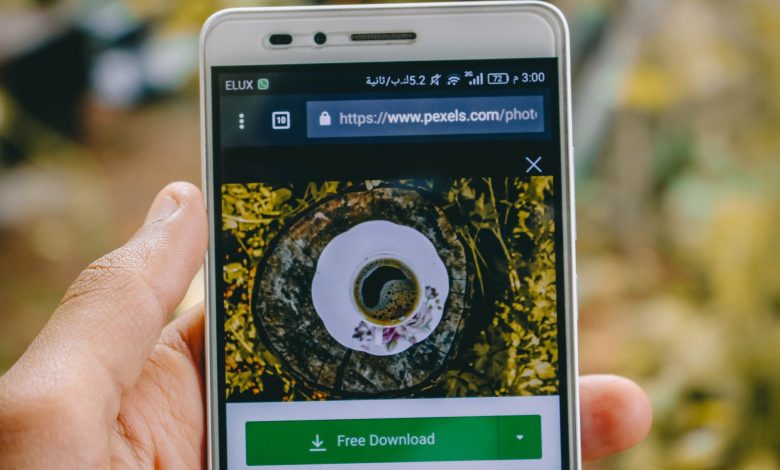 Close-up of a smartphone showing a coffee cup image on a screen outdoors.