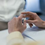 Close-up of hands holding a pen during a business meeting or contract signing.