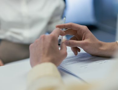 Close-up of hands holding a pen during a business meeting or contract signing.