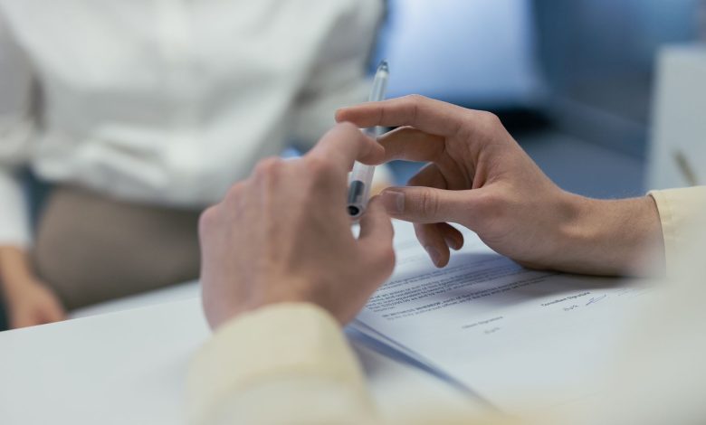 Close-up of hands holding a pen during a business meeting or contract signing.
