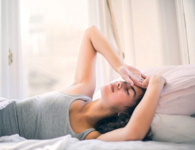 A woman relaxing on a bed, enjoying a peaceful morning with sunlight streaming in.