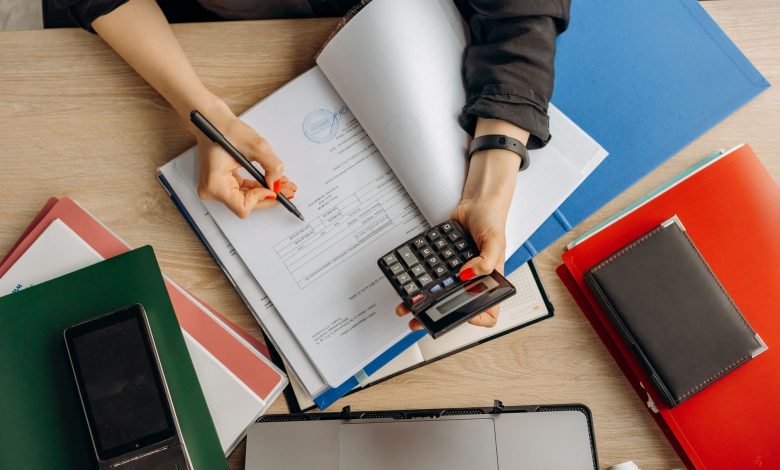 Accountant analyzing financial documents with a calculator on a desk, highlighting business tasks.