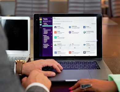 Two professionals collaborating using laptops and communication software in a business setting.