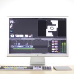 A sleek computer monitor displays video editing software in a modern workspace.