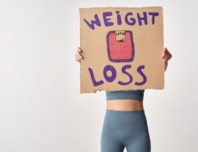 Person holding 'weight loss' sign for fitness motivation and health goals.