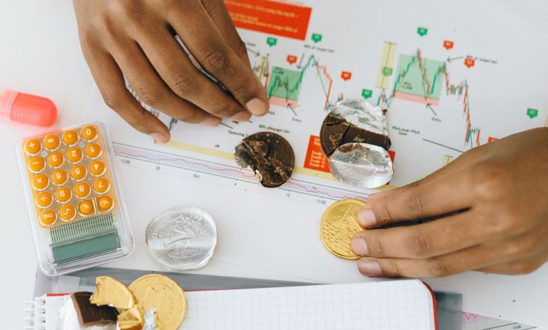 Analyzing financial charts with a calculator and chocolate coins.