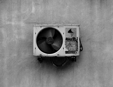 Monochrome image of a wall-mounted air conditioner on a concrete surface.