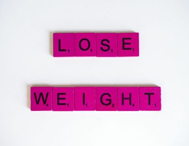 Creative image of the phrase 'Lose Weight' spelled with Scrabble tiles on a white background.