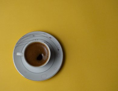 Stylish coffee cup with black coffee on a vibrant yellow background, perfect for modern design.