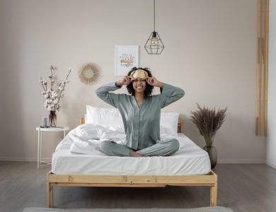 A smiling woman in pajamas enjoys a relaxed morning in bed, exuding happiness.